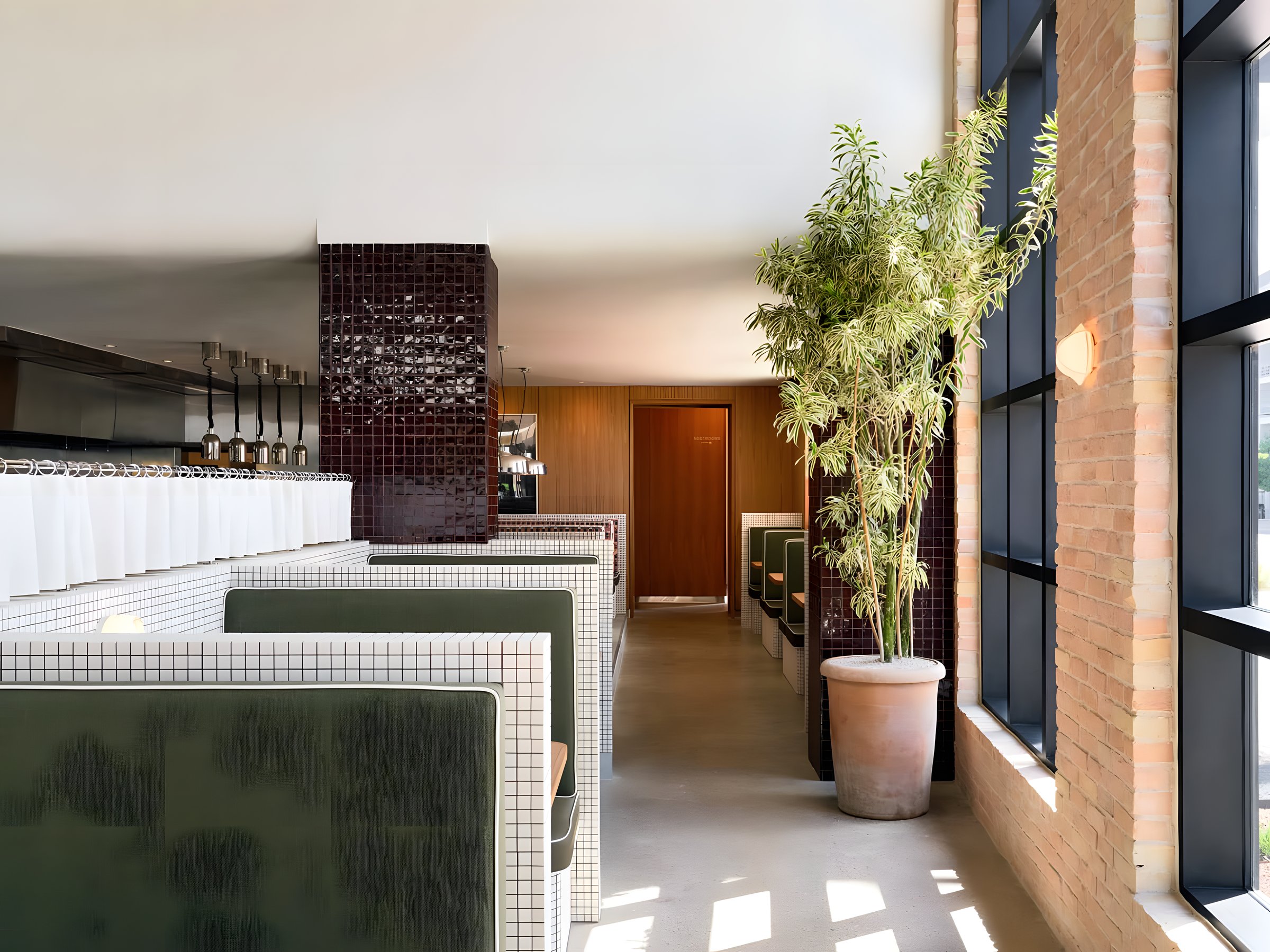 Paperboy restaurant interior — green leather booths, white tile, and tall brick windows on South Lamar