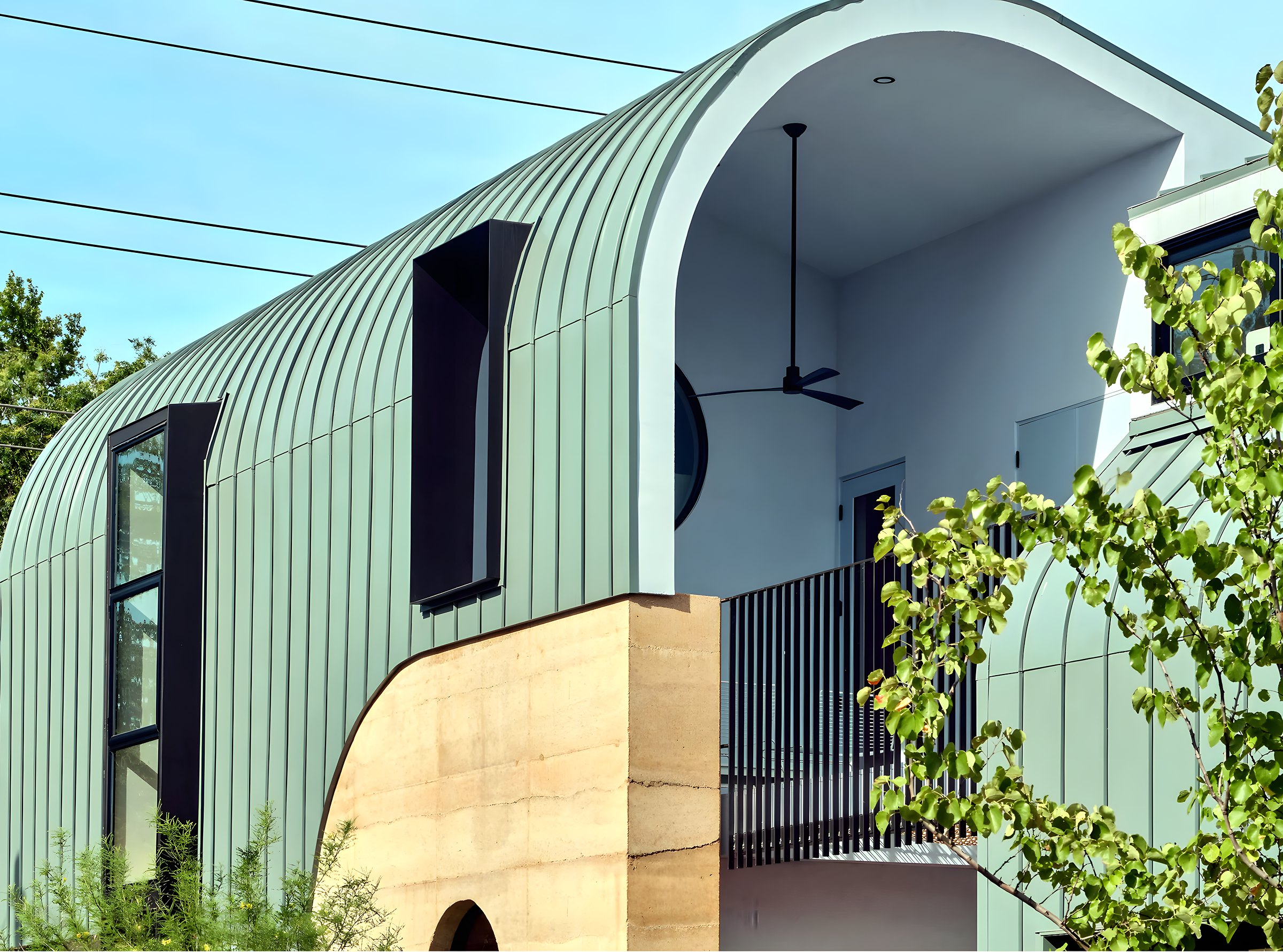 Curved standing-seam roof over rammed-earth walls in daylight